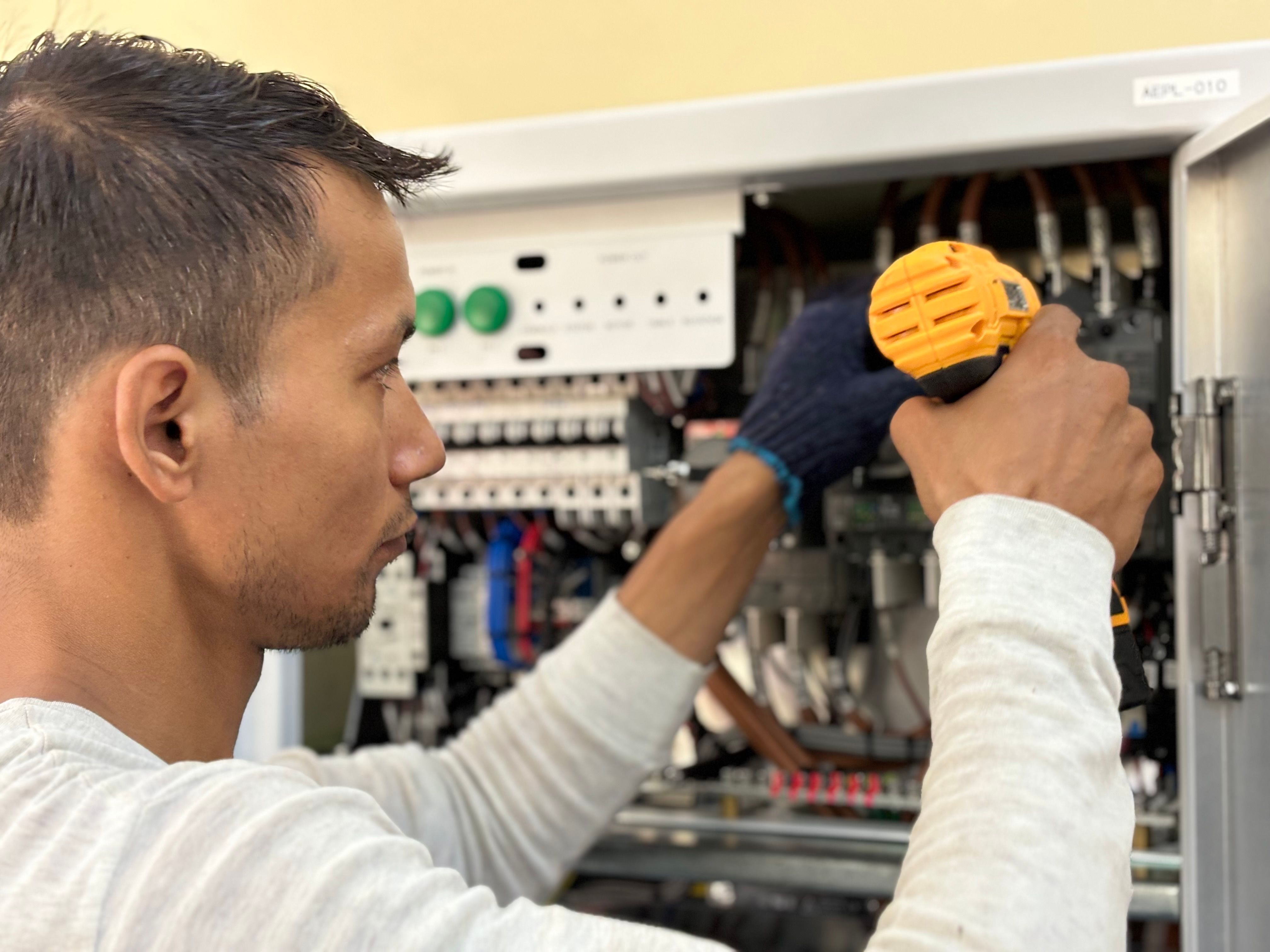 Technicus die met een schroevendraaier werkt aan een open schakelkast